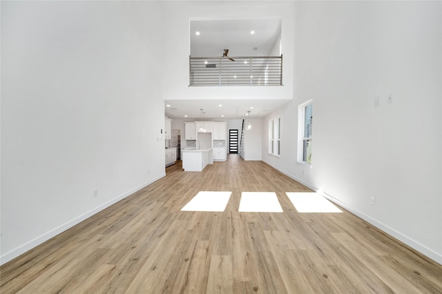 220 E Park St, Little Elm, TX 75068 - unfurnished living room featuring a high ceiling, light wood-style flooring, and baseboards
