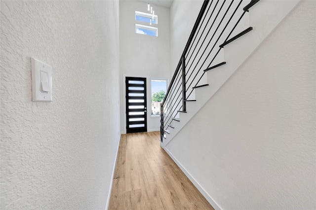 220 E Park St, Little Elm, TX 75068 - entrance foyer featuring baseboards, stairway, light wood-type flooring, a towering ceiling, and a textured wall