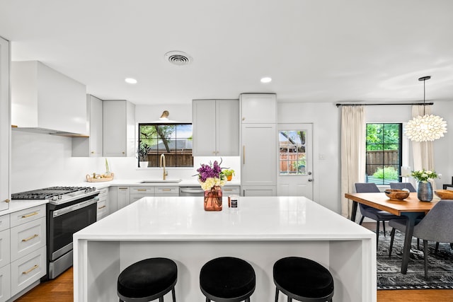 9115 Longmont Dr, Dallas, TX 75238 - kitchen with stainless steel gas range oven, a sink, a breakfast bar area, dark wood-type flooring, and recessed lighting