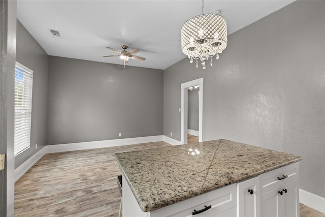 2721 Ave G, Fort Worth, TX 76105 - kitchen featuring ceiling fan, light wood-style floors, baseboards, white cabinets, and light stone counters