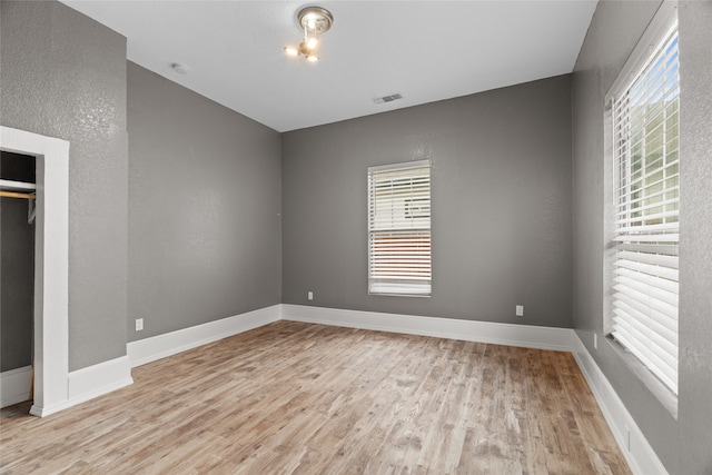 2721 Ave G, Fort Worth, TX 76105 - unfurnished bedroom with wood finished floors, multiple windows, baseboards, and a closet