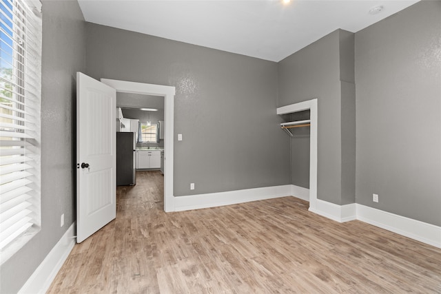 2721 Ave G, Fort Worth, TX 76105 - unfurnished bedroom featuring freestanding refrigerator, light wood finished floors, baseboards, and a closet