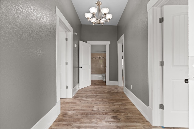 2721 Ave G, Fort Worth, TX 76105 - hall with a chandelier, wood finished floors, a textured wall, and baseboards