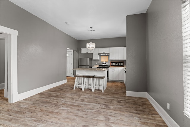 2721 Ave G, Fort Worth, TX 76105 - kitchen featuring stainless steel appliances, light wood-type flooring, under cabinet range hood, a center island, and a chandelier