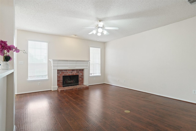 7104 Chandler Dr, Plano, TX 75024 - unfurnished living room featuring a ceiling fan, hardwood / wood-style floors, baseboards, a brick fireplace, and a textured ceiling