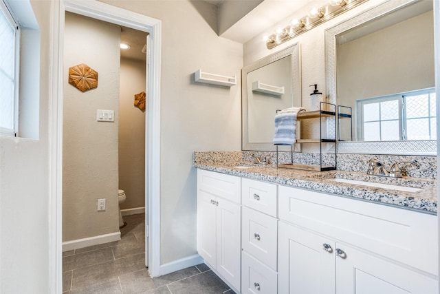 605 Sevilla Dr, Garland, TX 75043 - bathroom featuring baseboards, double vanity, toilet, and tile patterned floors