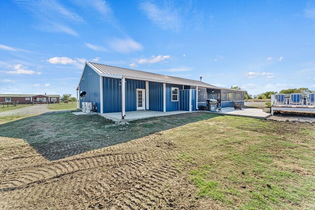 179 Johnston Dr, Decatur, TX 76234 - back of house with board and batten siding, a lawn, a patio, metal roof, and a sunroom