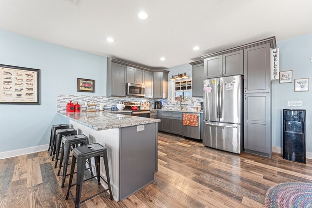 179 Johnston Dr, Decatur, TX 76234 - kitchen featuring stainless steel appliances, gray cabinetry, a peninsula, a kitchen breakfast bar, and tasteful backsplash