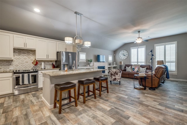 410 Phillips Ct, Mansfield, TX 76063 - kitchen with appliances with stainless steel finishes, backsplash, a breakfast bar, vaulted ceiling, and light wood-style flooring