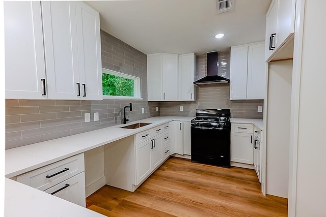 701 N Carrier Pkwy, Grand Prairie, TX 75050 - kitchen featuring wall chimney exhaust hood, black range with gas cooktop, a sink, white cabinets, and tasteful backsplash