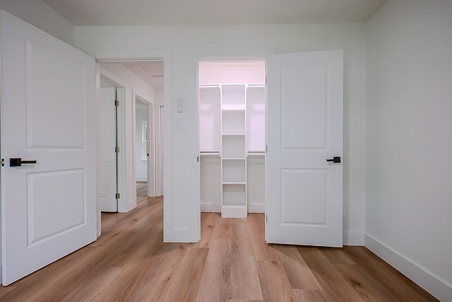 701 N Carrier Pkwy, Grand Prairie, TX 75050 - unfurnished bedroom with light wood-style floors, a walk in closet, a closet, and baseboards