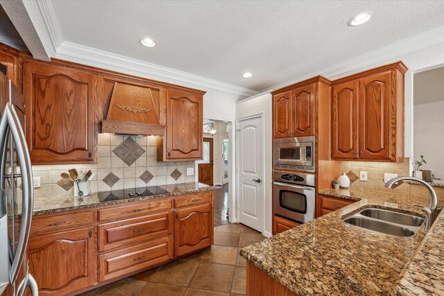104 Lost Oaks Dr, Waco, TX 76705 - kitchen with appliances with stainless steel finishes, a sink, crown molding, brown cabinetry, and dark stone counters