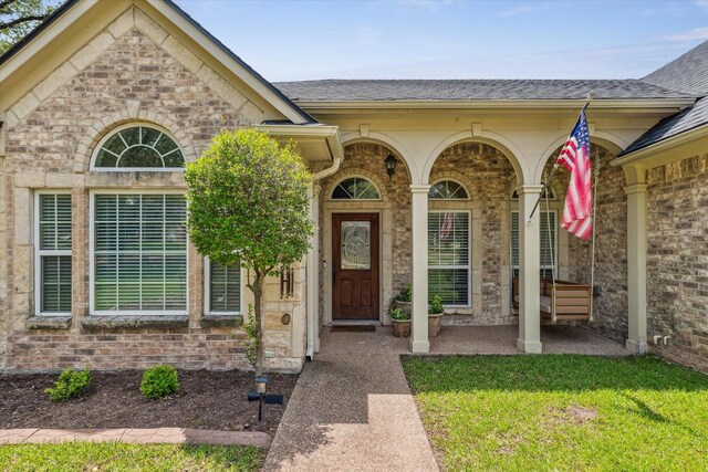 104 Lost Oaks Dr, Waco, TX 76705 - doorway to property featuring brick siding, roof with shingles, and a lawn
