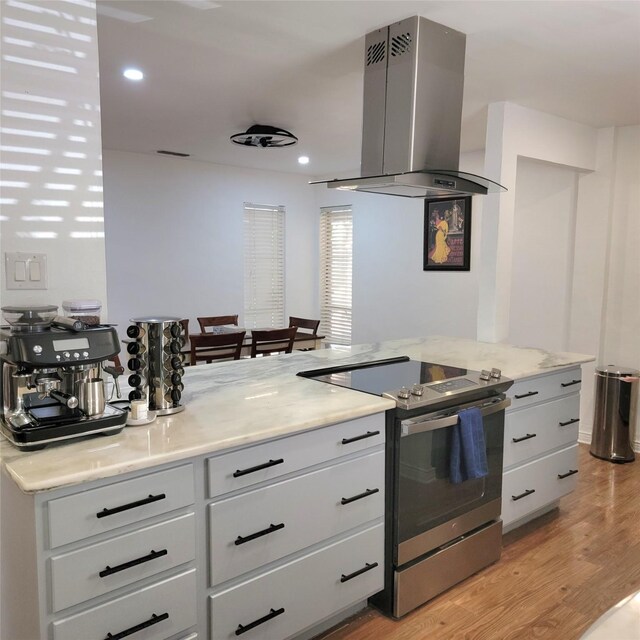15642 Overmead Cir, Dallas, TX 75248 - kitchen featuring electric range, island range hood, light wood-style flooring, white cabinets, and light stone counters