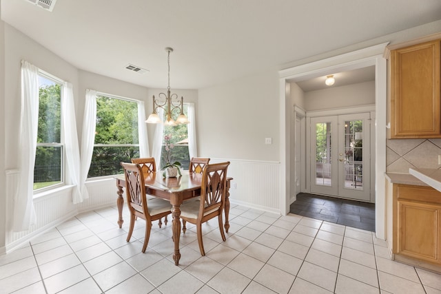 1928 Victoria Cir, Mckinney, TX 75072 - dining area featuring wainscoting, light tile patterned floors, a chandelier, and french doors