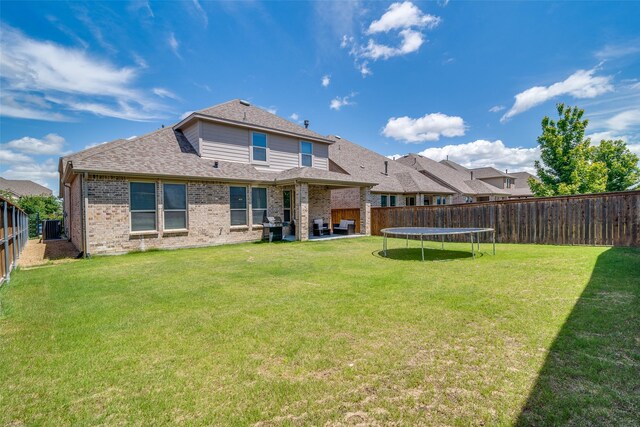 1822 Indigo Creek Ln, Wylie, TX 75098 - back of house with brick siding, roof with shingles, a patio area, and a trampoline