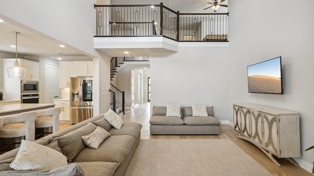 4190 Sandhills Ln, Prosper, TX 75078 - living room with stairs, light wood finished floors, a towering ceiling, baseboards, and ceiling fan