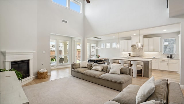 4190 Sandhills Ln, Prosper, TX 75078 - living area featuring a towering ceiling, light wood-type flooring, a glass covered fireplace, and recessed lighting