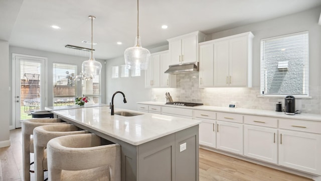 4190 Sandhills Ln, Prosper, TX 75078 - kitchen with a sink, under cabinet range hood, gas cooktop, an island with sink, and light wood finished floors
