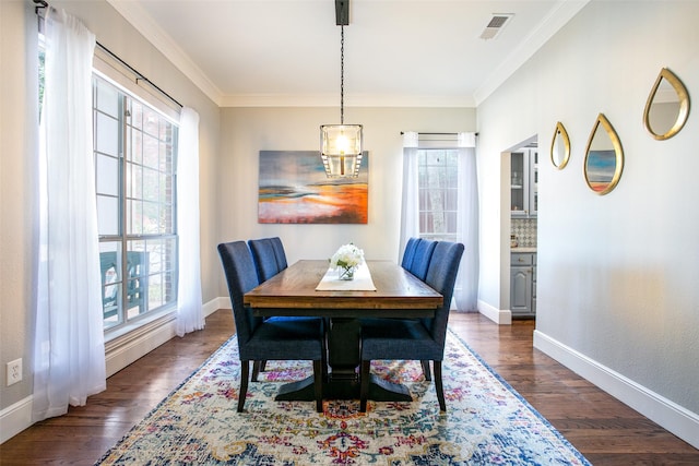 dining room with plenty of natural light, dark wood finished floors, ornamental molding, baseboards, and a chandelier
