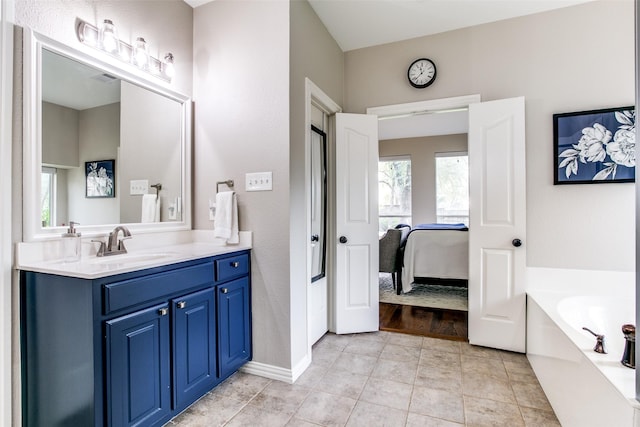 ensuite bathroom featuring vanity, a bath, baseboards, and tile patterned flooring