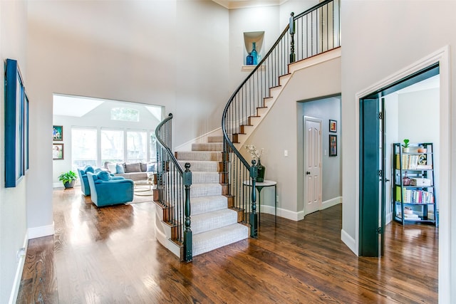 staircase with a high ceiling, wood finished floors, and baseboards