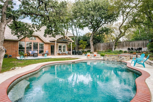 view of pool featuring a patio area, an outdoor living space, fence, and a pool with connected hot tub