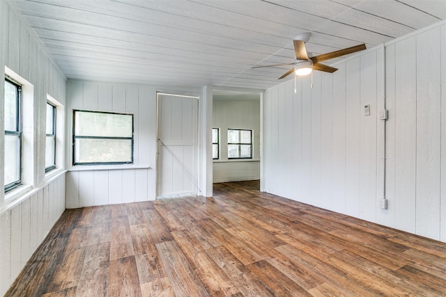 unfurnished room featuring wood finished floors, ceiling fan, and wood walls