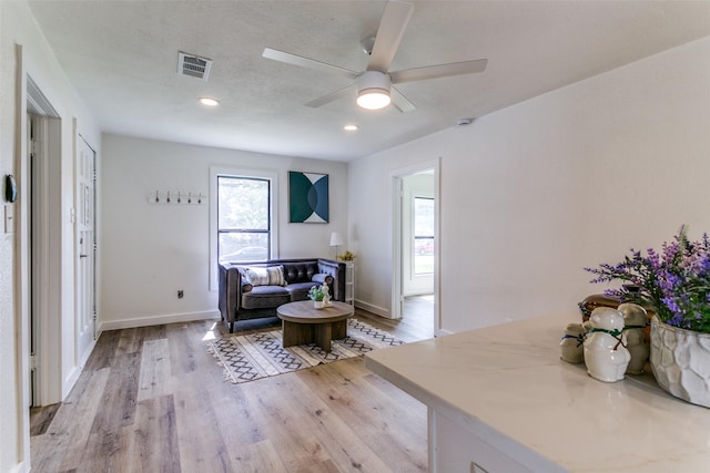 living area with light wood finished floors, a ceiling fan, baseboards, and recessed lighting