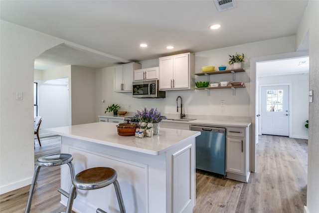 kitchen featuring appliances with stainless steel finishes, a sink, light wood-style flooring, white cabinets, and recessed lighting