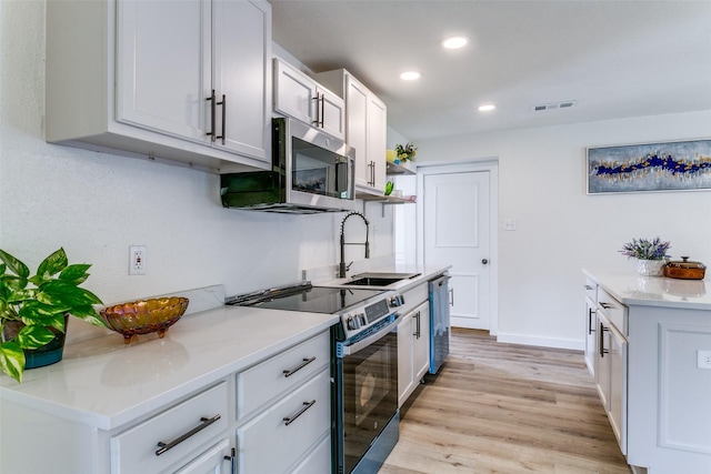 kitchen featuring appliances with stainless steel finishes, recessed lighting, light wood-style floors, light countertops, and a sink