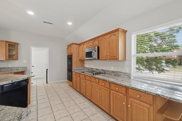 301 Angela Dr, Burleson, TX 76028 - kitchen with black appliances, light stone countertops, light tile patterned floors, glass insert cabinets, and brown cabinets