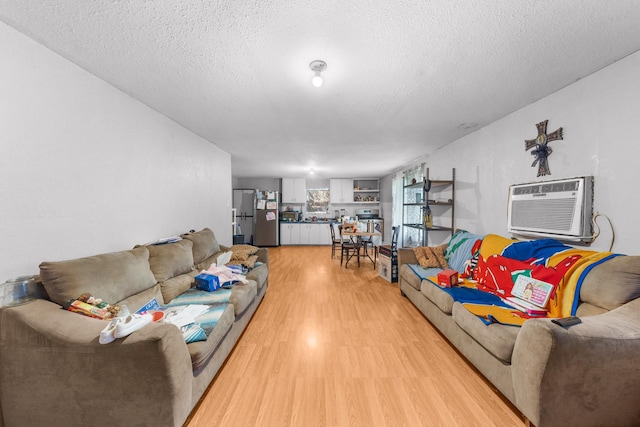 14581 Texas Highway 11 E, Pickton, TX 75471 - living room featuring light wood finished floors, an AC wall unit, and a textured ceiling