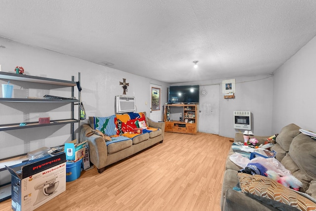 14581 Texas Highway 11 E, Pickton, TX 75471 - living room with heating unit, wood finished floors, a textured ceiling, and a wall mounted air conditioner