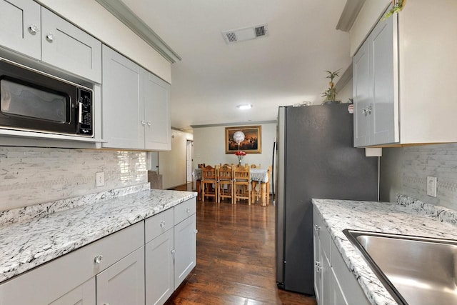 805 Loganwood Dr, Royse City, TX 75189 - kitchen featuring black microwave, backsplash, dark wood-type flooring, and freestanding refrigerator