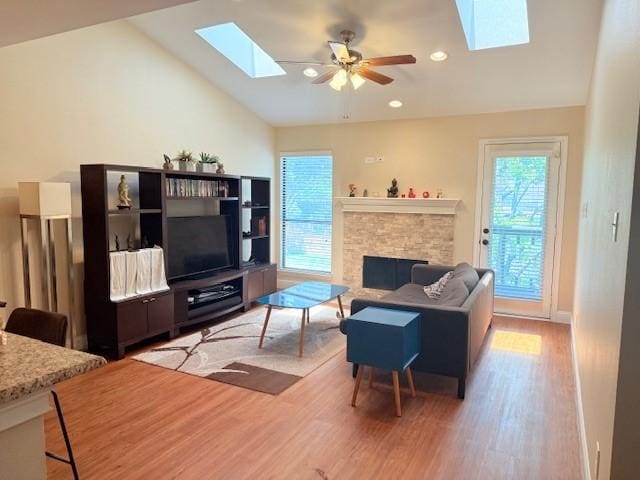 5616 Preston Oaks Rd Unit 110, Dallas, TX 75254 - living room featuring a skylight, light wood-type flooring, a stone fireplace, ceiling fan, and recessed lighting