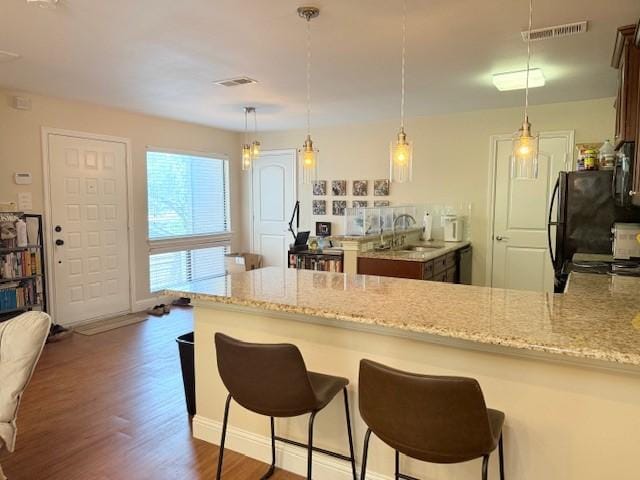 5616 Preston Oaks Rd Unit 110, Dallas, TX 75254 - kitchen featuring a sink, light stone countertops, a peninsula, dark wood-style flooring, and black appliances