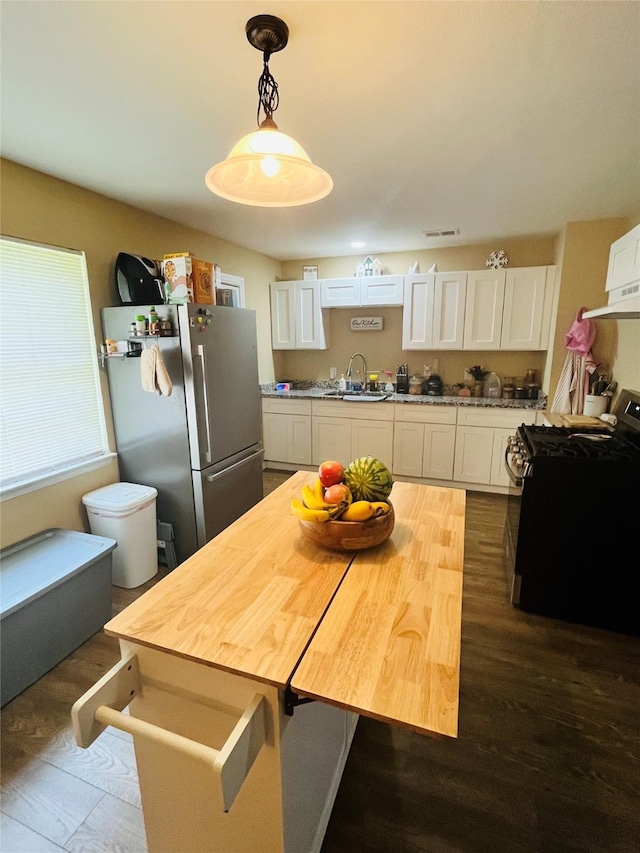 kitchen featuring appliances with stainless steel finishes, white cabinetry, a sink, dark wood finished floors, and pendant lighting