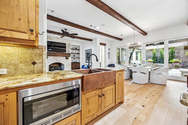 933 Glenhurst Rd, Keller, TX 76248 - kitchen featuring stainless steel microwave, open floor plan, a sink, a stone fireplace, and beam ceiling