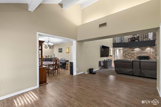 4403 Nassau Dr, Wichita Falls, TX 76308 - living room featuring a chandelier, wood finished floors, a towering ceiling, a stone fireplace, and beam ceiling