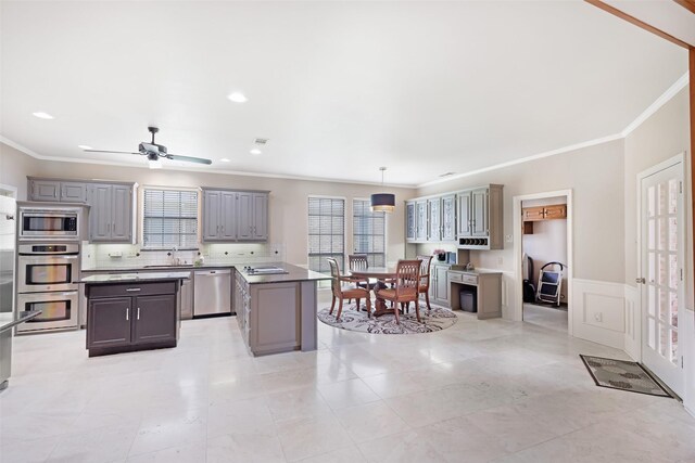 3213 Louis Dr, Plano, TX 75023 - kitchen featuring gray cabinets, appliances with stainless steel finishes, a kitchen island, crown molding, and decorative backsplash