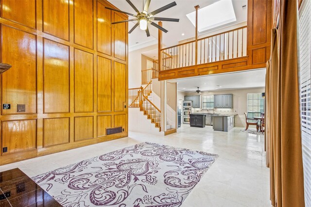 3213 Louis Dr, Plano, TX 75023 - unfurnished living room with ceiling fan, stairs, a skylight, ornamental molding, and a towering ceiling
