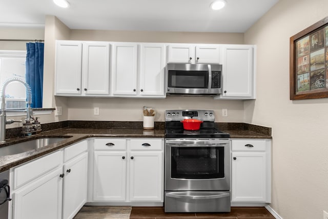 8308 Montecito Dr, Denton, TX 76210 - kitchen featuring appliances with stainless steel finishes, a sink, white cabinetry, dark stone countertops, and recessed lighting