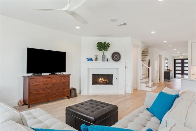 477 Willow Moon Ranch Rd, Crawford, TX 76638 - living room featuring a ceiling fan, stairway, light wood-type flooring, recessed lighting, and a warm lit fireplace
