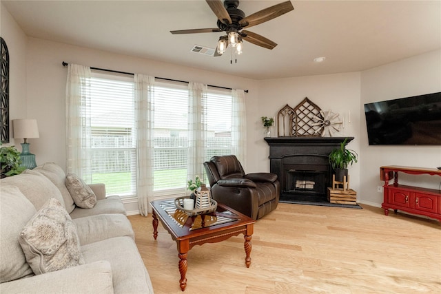 10617 Big Oak Dr, Fort Worth, TX 76131 - living area featuring light wood-type flooring, a ceiling fan, a fireplace with raised hearth, and baseboards