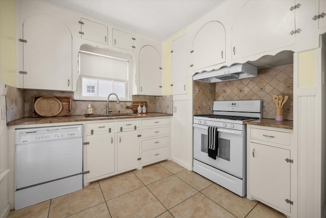 kitchen featuring white appliances, under cabinet range hood, a sink, backsplash, and light tile patterned floors