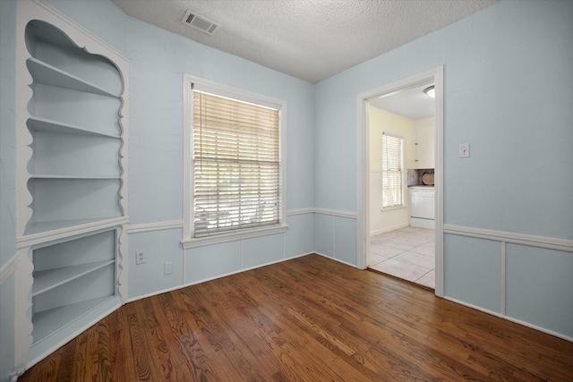 empty room featuring wood finished floors, plenty of natural light, and a textured ceiling