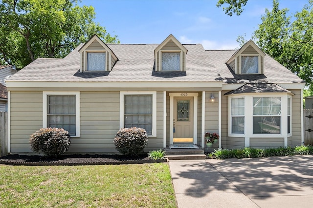 cape cod-style house with roof with shingles and a front yard