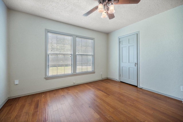 unfurnished room featuring a ceiling fan, hardwood / wood-style floors, a textured ceiling, and baseboards