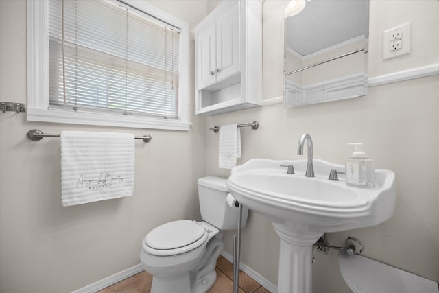 bathroom with toilet, baseboards, and tile patterned flooring